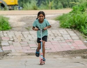 girl riding scooter on paved path outdoors